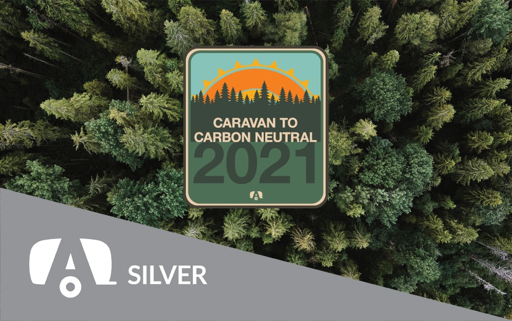 Silver tag with the Caravan to Carbon Neutral sticker on a tree background